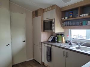 a small kitchen with a sink and a microwave at 10 Berth on Seaview (Linwood) in Ingoldmells