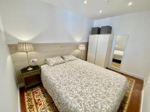コルネリャー・デ・リョブレガートにあるSuite Apartment Anselm Barcelonaのベッドルーム(ベッド1台、ランプ、鏡付)