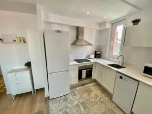 a white kitchen with a refrigerator and a sink at Suite Apartment Anselm Barcelona in Cornellà de Llobregat