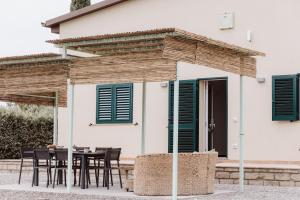Casa con persianas verdes, mesa y sillas en Bioagriturismo Terra d'Angeli, en Bagno Roselle