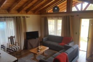 ein Wohnzimmer mit einem Sofa und einem Tisch in der Unterkunft Tranquilidad y descanso en Villarrica - Pucón in Pucón