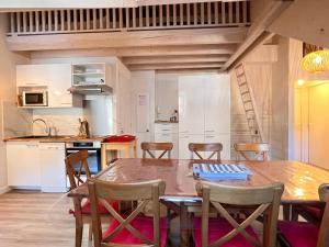 uma cozinha e sala de jantar com uma mesa de madeira e cadeiras em Place de la mairie T2 type loft 70m2 terrasse 35m2 em Cauterets