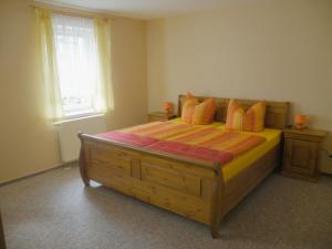 um quarto com uma grande cama de madeira com almofadas laranja em Am Lindenbaum em Kirnitzschtal