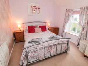 a bedroom with a bed and two windows at Ghyll Cottage in Rosedale Abbey