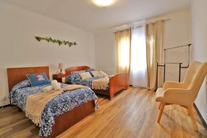 a bedroom with two beds and a chair at Casa das Vinhas in Mosteiros