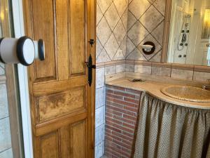Łazienka z drewnianymi drzwiami i umywalką w obiekcie La Helguera Vivienda Vacacional w mieście Villanueva
