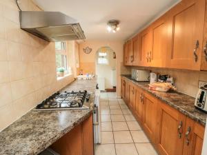 a kitchen with wooden cabinets and a stove top oven at Hogwarts Cottage in Pickering