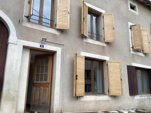 ein Gebäude mit Fensterläden aus Holz und einer Tür in der Unterkunft Maison spacieuse et familiale in Pexonne