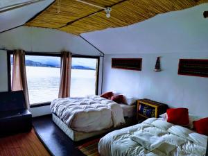 a bedroom with two beds and a large window at Titicaca wasy lodge in Puno