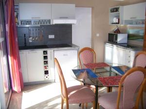 a kitchen with a glass table and chairs and a counter at Rez-de-jardin 50 m² entre Biarritz et Capbreton in Ondres