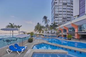 uma piscina num hotel com cadeiras e mesas em Gamma Acapulco Copacabana em Acapulco