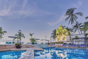 a pool at a resort with palm trees at Gamma Acapulco Copacabana in Acapulco