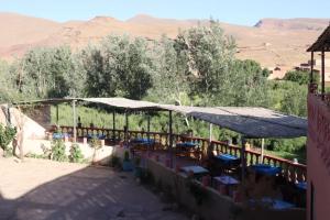 eine Terrasse mit Tischen und Sonnenschirmen in der Wüste in der Unterkunft Maison d'hôtes La vallée des nomades in Semrir