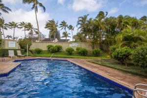 a swimming pool in a yard with palm trees at Beach Cozy North Shore Turtle Bay Condo in Kahuku