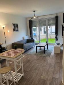 uma sala de estar com um sofá e uma mesa em Appartement F2 de haut standing en hypercentre avec jardin privé à 270 m de la Gare de MANTES ! em Mantes-la-Ville
