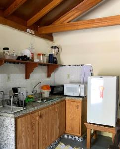 a kitchen with wooden cabinets and a white refrigerator at Sitio dos Palmitos - Chalé Palmeira Real in Domingos Martins