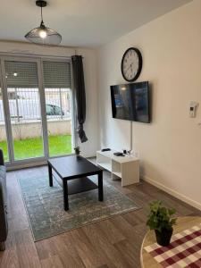 uma sala de estar com uma mesa e um relógio na parede em Appartement F2 de haut standing en hypercentre avec jardin privé à 270 m de la Gare de MANTES ! em Mantes-la-Ville