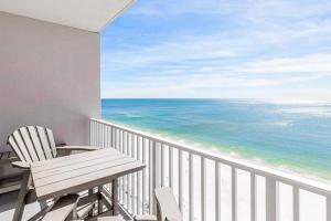 Un balcón con una silla de madera y el océano en Windemere Condominiums II en Pensacola