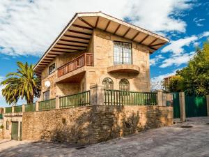 a stone house with a balcony on a wall at Spacious holiday home in Santiago de Compostela with pool in Eirapedriña