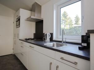 een witte keuken met een wastafel en een raam bij Modern house with roof, located in a holiday park in Rhenen in Rhenen