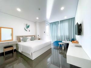 een slaapkamer met een groot wit bed en een televisie bij Olivia Hotel and Apartment in Nha Trang