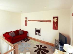 een woonkamer met een rode bank en een tv bij Cow Byre Cottage in Pickering