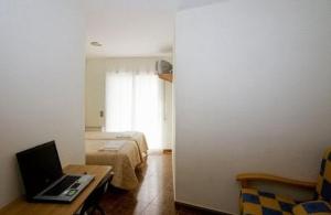 1 dormitorio con cama y escritorio con ordenador portátil en Amolls Restaurant i Habitacions, en Olot