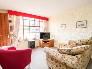 a living room with a couch and a tv at The Coach House in Kirkoswald