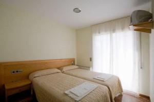 a hotel room with two beds and a window at Amolls Restaurant i Habitacions in Olot