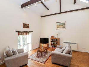 Una sala de estar con dos sillas y un televisor. en The Old School Room, en Chelborough