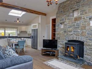 a living room with a stone fireplace and a television at Farmhouse in Lisdoonvarna