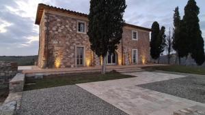 ein großes Steinhaus mit einem Baum davor in der Unterkunft Casa Insieme in Asciano