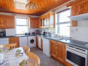 une cuisine avec des placards en bois et une table avec des chaises dans l'établissement Seaview Cottage, à Ballyvaughan