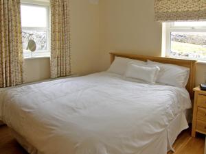 a white bed in a bedroom with a window at Dolmen Cottage in Kilfenora