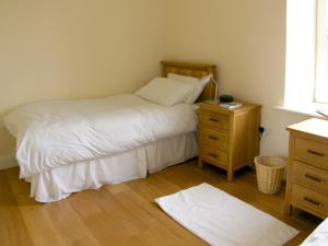 a bedroom with a bed and a wooden night stand at Dolmen Cottage in Kilfenora