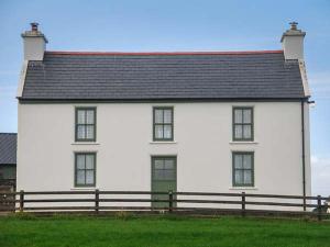 ein großes weißes Haus mit schwarzem Dach in der Unterkunft Nellie's Farmhouse in Bantry