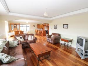 uma sala de estar com um sofá e uma televisão em Cloonacastle Cottage em Ballinrobe