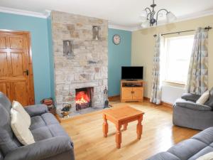 a living room with a fireplace and a couch and a table at Tieve Baun in Ballaghnatrillick