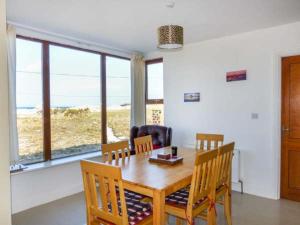 uma sala de jantar com uma mesa e cadeiras e uma janela em 6 Strand Cottages em Doogort