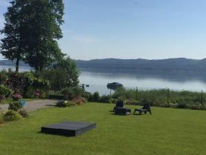 a lawn with two chairs and a table and a boat in the water at Cottage by the lake in Nadole in Nadole