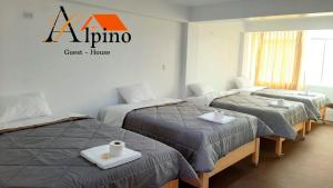 una habitación de hotel con 3 camas y un cartel en la pared en Alpino Guest House en Huaraz