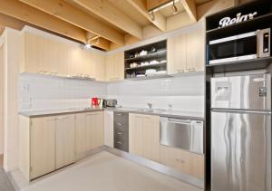 a kitchen with wooden cabinets and a stainless steel refrigerator at Pinot in Dinner Plain