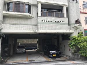 two cars parked in a parking lot in front of a building at Second Habor Beach House in Naha