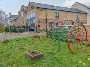 a garden with a tractor in front of a building at The Hay Barn in Houghton le Spring