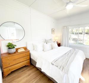 a white bedroom with a large bed and a mirror at Waukivory Estate - The Cottage 