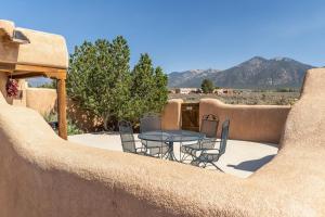 a patio with a table and chairs in the desert at Casa Allis Taos in El Prado