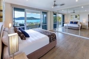 a bedroom with a large bed and glass walls at Beach Lodges in Hamilton Island