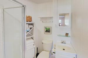 a white bathroom with a toilet and a sink at Haleiwa Cottage in Haleiwa
