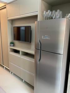 a stainless steel refrigerator in a kitchen with a tv at Lindo Studio Matinhos Prédio na beira mar. in Matinhos
