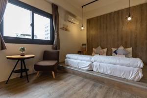 a large bed in a room with a table and a chair at Cozy House Hostel in Hualien City